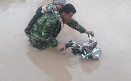 صورة تهز المشاعر.. طفل يتشبث بوالده وسط سيول وادي كنحان بلحج