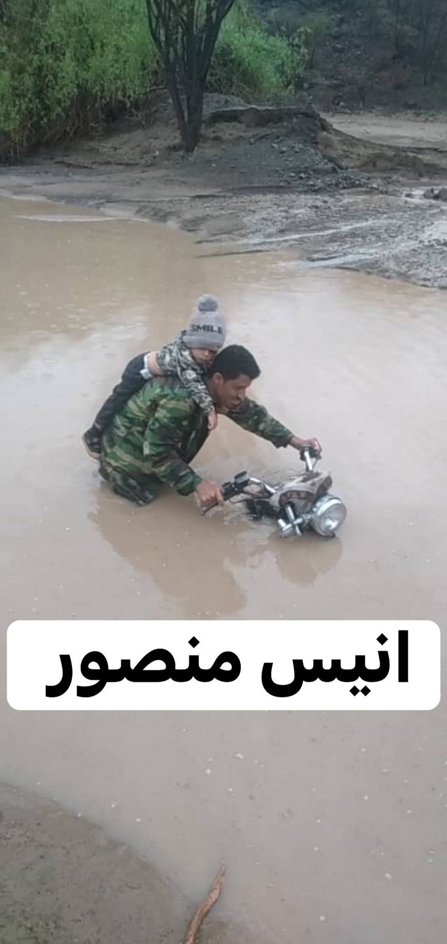 صورة تهز المشاعر.. طفل يتشبث بوالده وسط سيول وادي كنحان بلحج